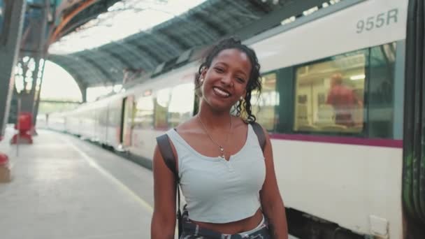 Усміхнена Молода Змішана Жінка Стоїть Залізничній Станції Фоні Поїздів — стокове відео
