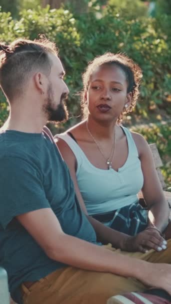 Vertical Video Interracial Couple Talking While Sitting Bench Backlight — Stockvideo