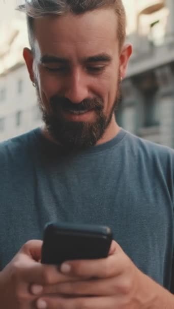 Vertical Video Young Smiling Man Beard Stands Street Using Cellphone — Αρχείο Βίντεο