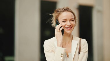 Close up, smiling businesswoman with blond hair talking on cellphone