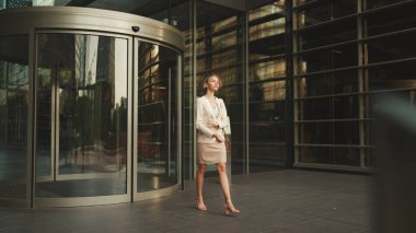 Businesswoman with blond hair wearing beige suit leaving business center