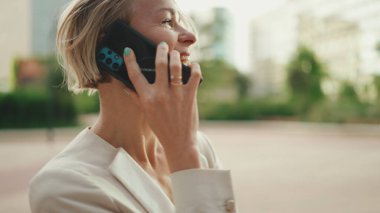 Happy businesswoman with blond hair talking on cellphone, good deal, success