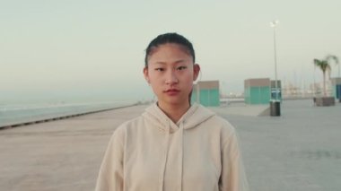 Asian girl wearing sportswear looking at camera at morning time. Camera moving forwards