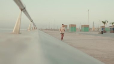 Asian young athletic woman running along the promenade. Sportswoman in sportswear exercising outdoors at morning time