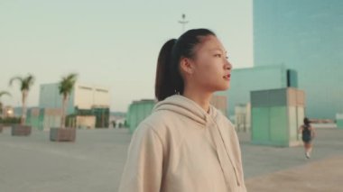 Asian young athletic woman in sportswear walking outdoors at morning time