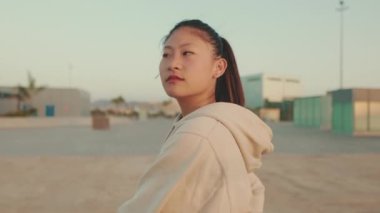 Asian girl in sportswear does workout, stretching and gymnastics at morning time on modern buildings background