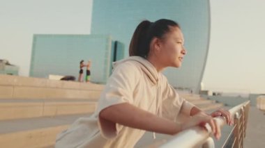 Asian girl in sportswear doing workout, push-ups on modern buildings background at morning time