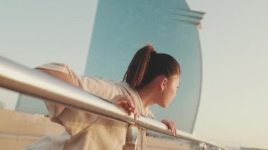 Asian girl in sportswear doing workout, push-ups on modern buildings background at morning time