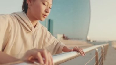 Asian girl in sportswear doing workout, push-ups on modern buildings background at morning time