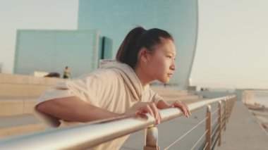 Asian girl in sportswear doing workout, push-ups on modern buildings background at morning time
