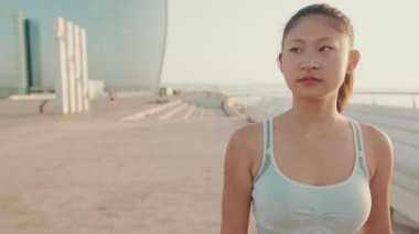 Close up, asian girl in sports top walking outside at morning time