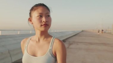 Close up, asian girl in sports top walking outside at morning time