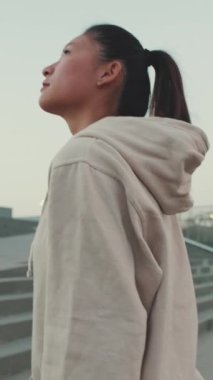 VERTICAL VIDEO: Asian girl wears sportswear, climbs the stairs at morning time