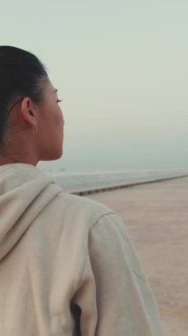 VERTICAL VIDEO: Asian girl wears sportswear walking outside at morning time