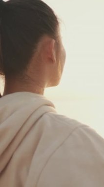 VERTICAL VIDEO: Close up, asian girl in sportswear doing workout, breathing exercises, relaxing at morning time