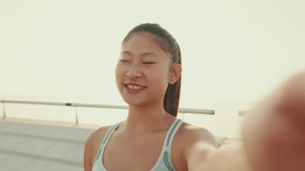 Smiling Asian Girl Sports Top Makes Selfie While Standing Embankment — ストック動画