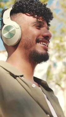 Close up, young male student wearing an olive colored shirt listening to music with headphones