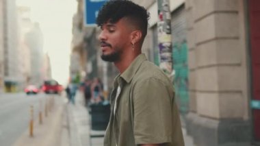 Young man with beard dressed in an olive-colored shirt crosses the road at pedestrian crossing