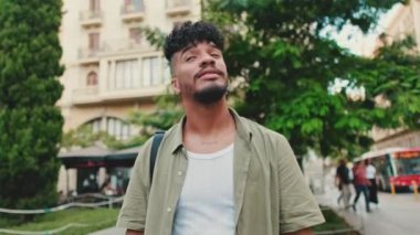 Young happy man with beard dressed in an olive-colored shirt walks along the street of the old city, looks to the side
