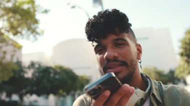 Close up, young man with beard wearing an olive colored shirt with headphones sends voice message