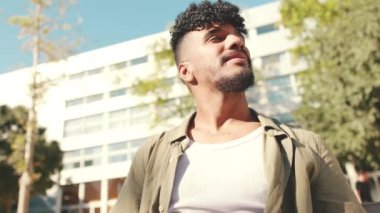 Close up, young male student wearing an olive colored shirt looks up and smiles