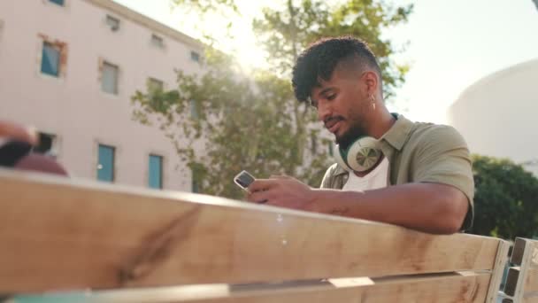 Young Man Beard Wearing Olive Colored Shirt Headphones Sits Bench — Vídeos de Stock