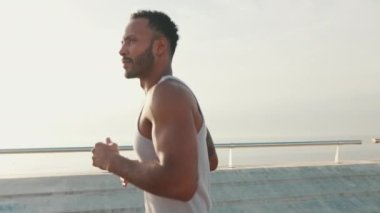 Yakından, genç sakallı erkek sporcu gezinti güvertesi boyunca koşuyor.