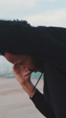 Genç sakallı erkek sporcu, antrenmandan önce setin üzerinde durarak ısınıyor.