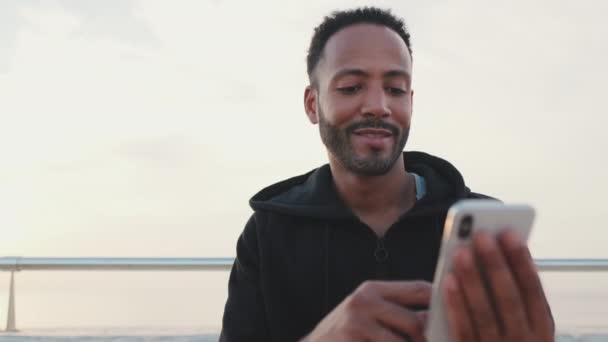 Close Young Smiling Bearded Male Athlete Dressed Hoodie Uses Cellphone — Stok Video