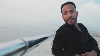 Genç sakallı erkek sporcu antrenmandan sonra sette otururken dinleniyor.