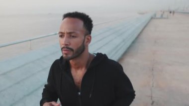Close up, young bearded male athlete runs along the promenade