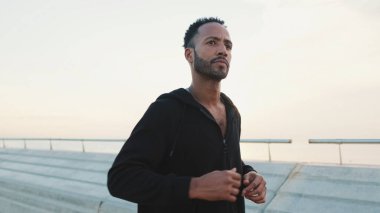 Genç sakallı erkek sporcu gezinti güvertesinde koşuyor.