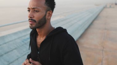 Genç sakallı erkek sporcu gezinti güvertesinde koşuyor.