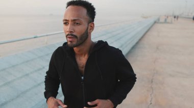 Genç sakallı erkek sporcu gezinti güvertesinde koşuyor.