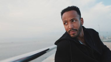 Genç sakallı erkek sporcu antrenmandan sonra sette otururken dinleniyor.