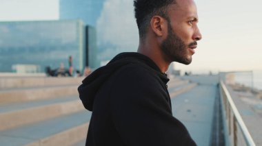 Genç sakallı erkek sporcu setin üzerinde durmuş denize bakıyor.. 