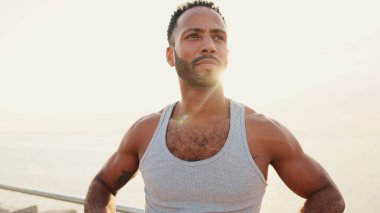 Genç sakallı, formda bir sporcu, deniz altyapısının tepesinde duruyor.