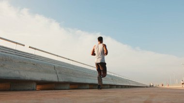 Genç sakallı, formda bir sporcu gezinti güvertesi boyunca koşar.