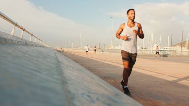 Genç sakallı, formda bir sporcu gezinti güvertesi boyunca koşar.