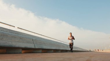 Young bearded male fit athlete runs along the promenade