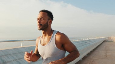 Young bearded male fit athlete runs along the promenade