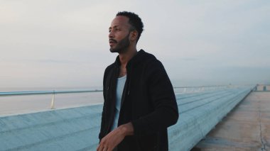 Genç sakallı erkek sporcu sette yürüyor.