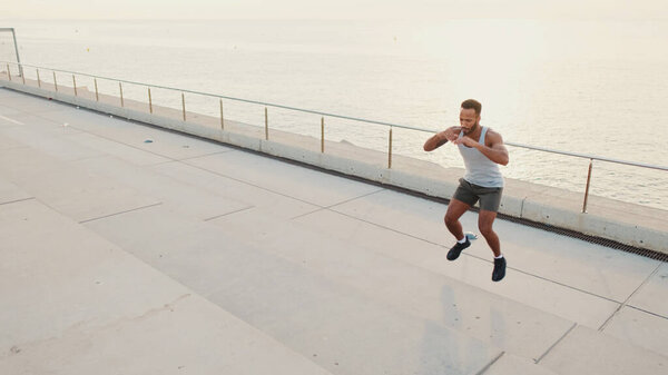 Young bearded male athlete doing workout, jumping on steps