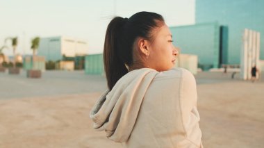 Asian girl in sportswear doing workout at morning time, stretching on modern buildings background