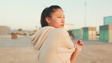 Asian girl in sportswear doing workout at morning time, stretching on modern buildings background