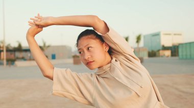 Asian girl in sportswear doing workout at morning time, stretching on modern buildings background