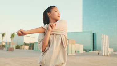 Asian girl in sportswear doing workout at morning time, stretching on modern buildings background