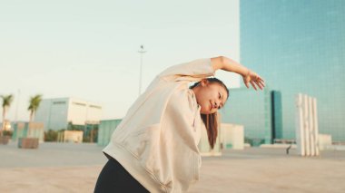 Asian girl in sportswear doing workout at morning time, stretching on modern buildings background