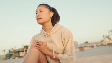 Asian girl in sportswear does workout, stretching and gymnastics on modern buildings background