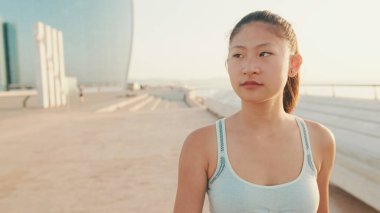 Asian girl in sports top walking outside at morning time